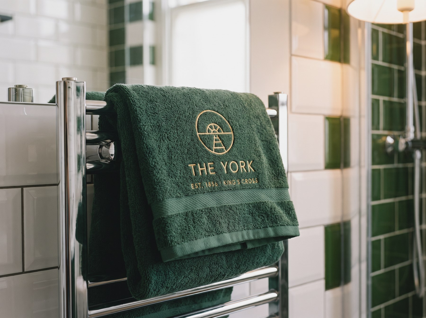 A green towel on a rail, embroidered with the mark