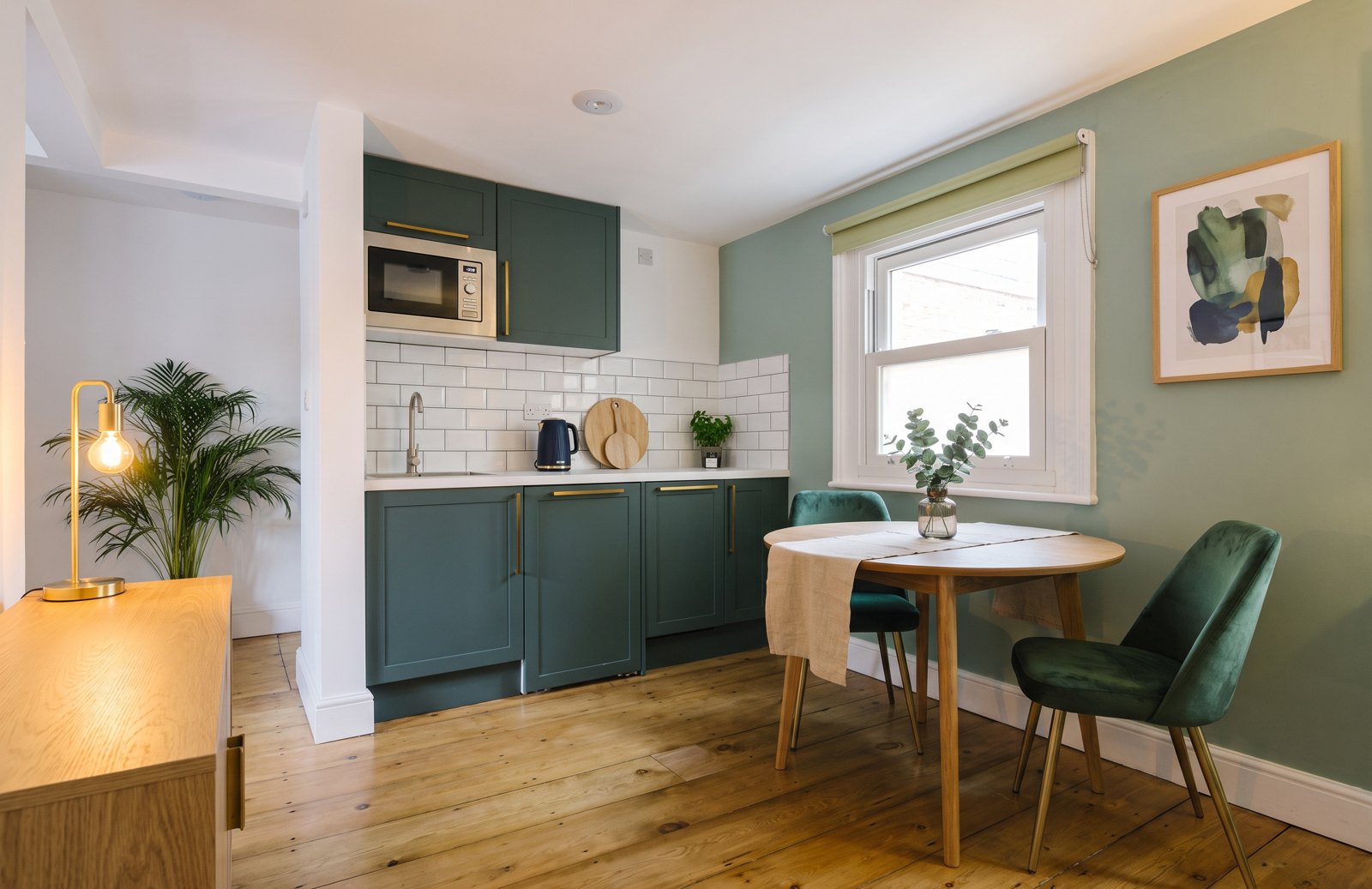 After: an oak table with green velvet chairs and an oak sideboard with a lamp