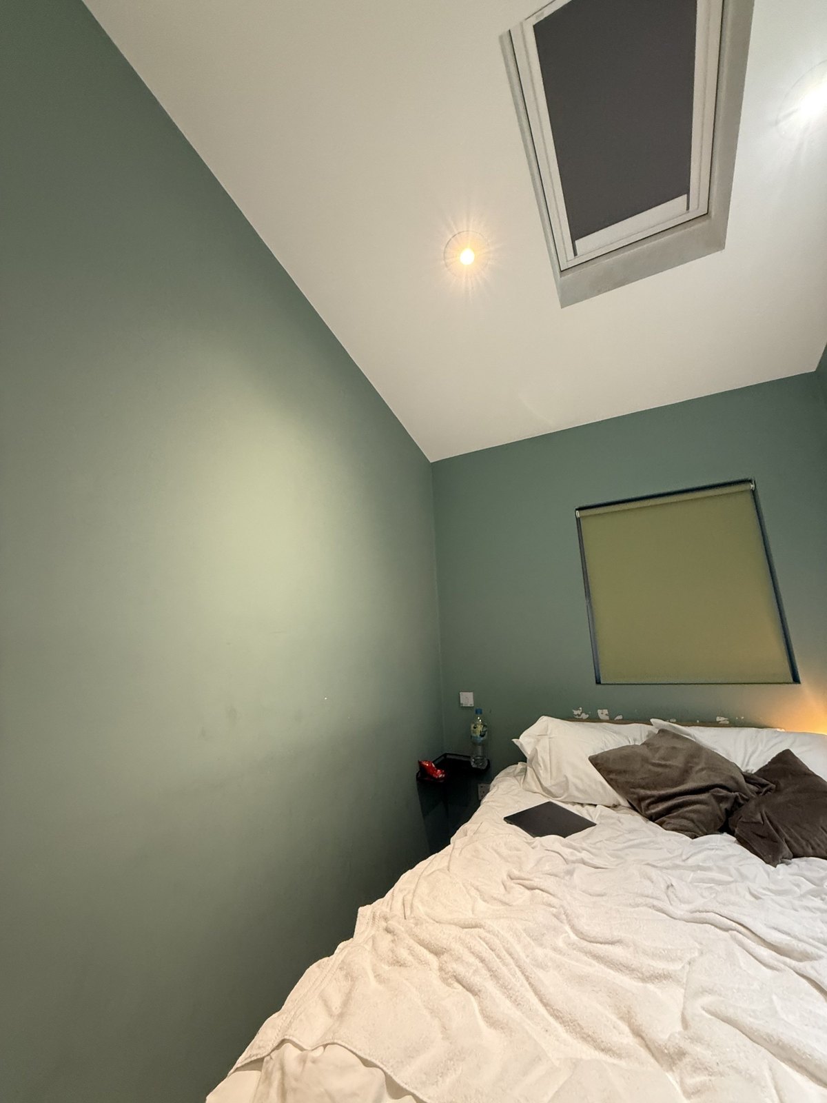 Before: the skylight bedroom with an unmade bed