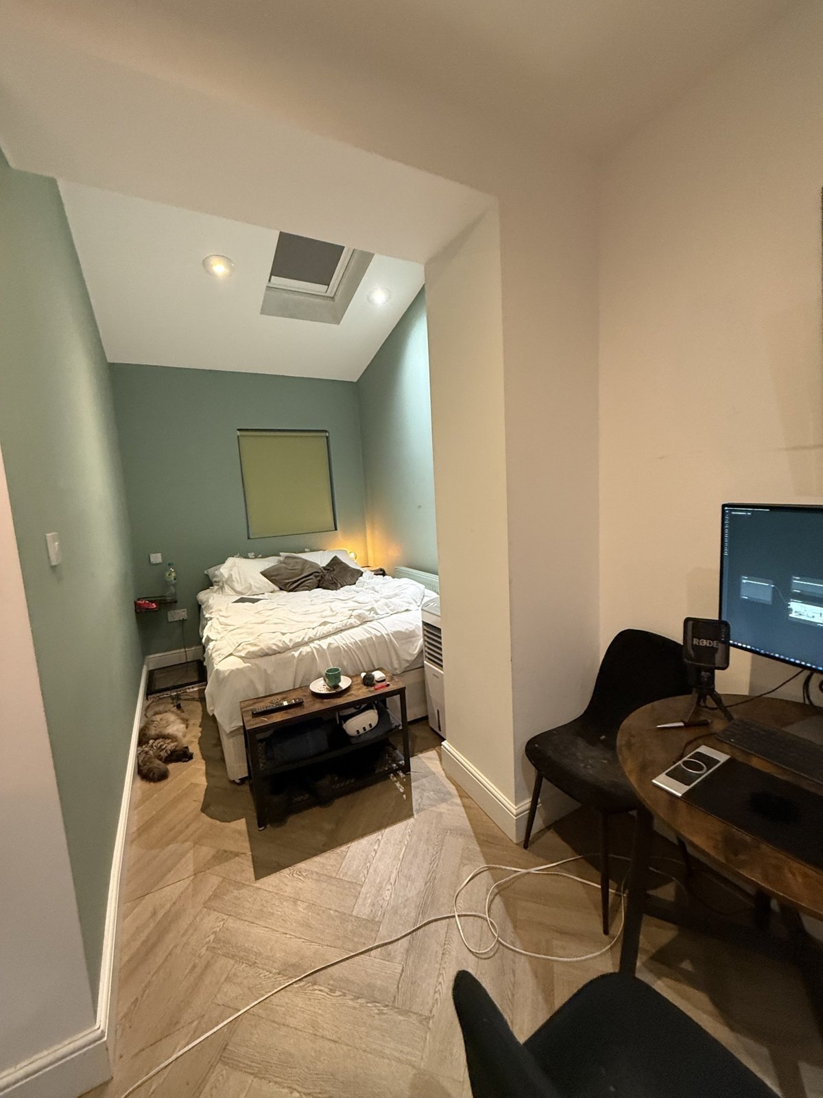 Before: the living area with a round table, a computer and cables, and the open bedroom beyond