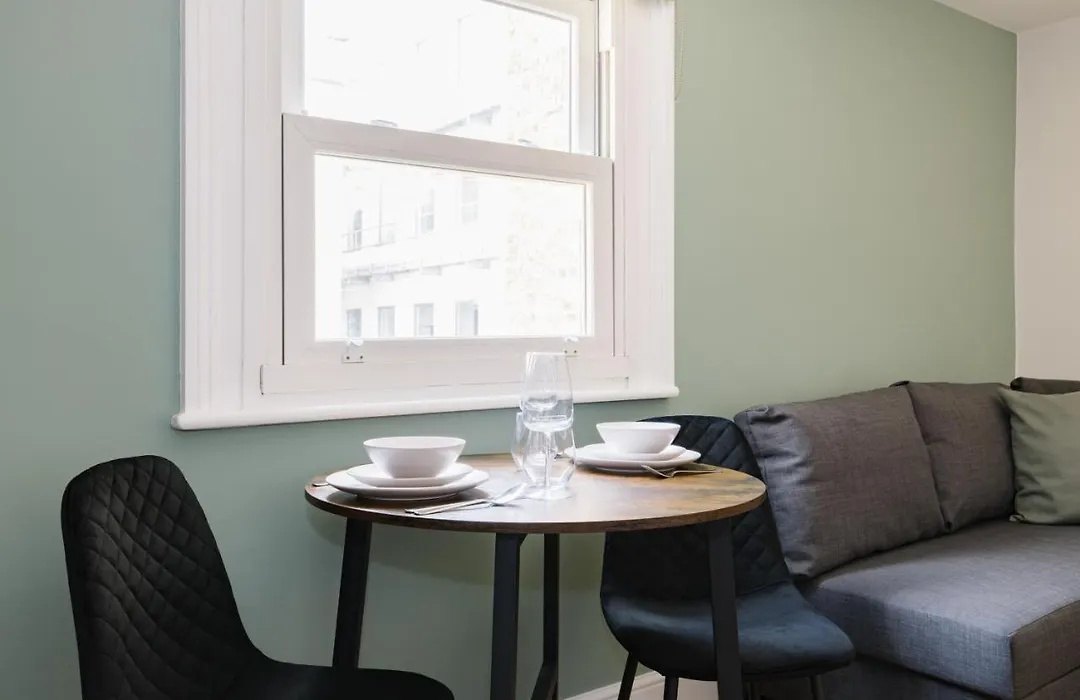 Before: a grey sofa and a small round table by the sash window