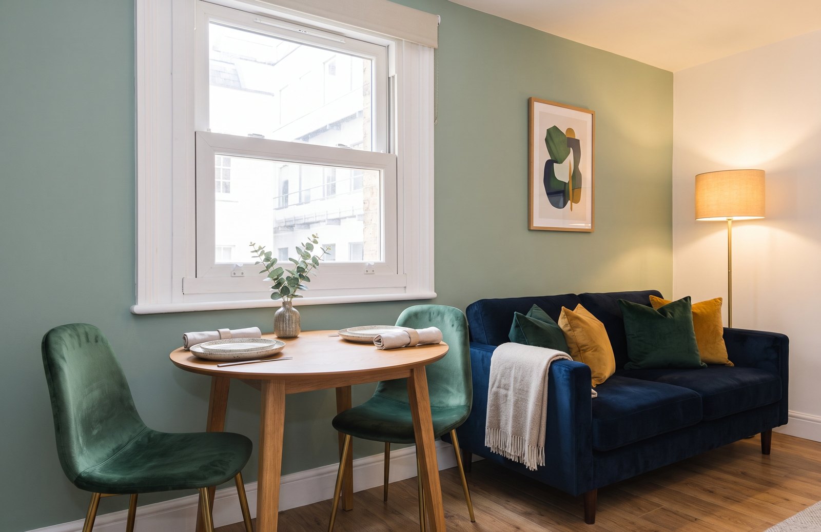 After: a navy velvet sofa, green velvet chairs and a set oak table