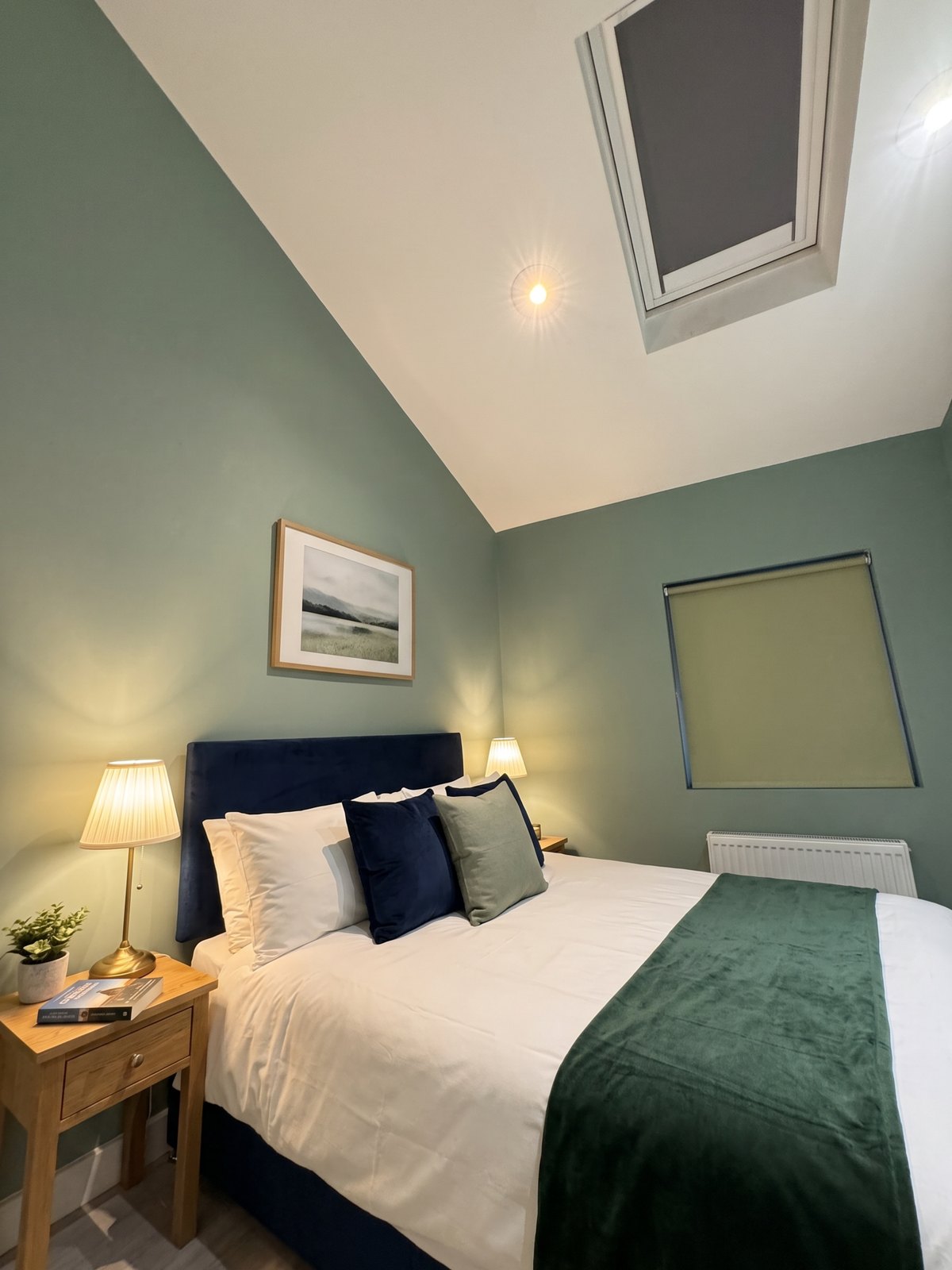After: the same bedroom with a velvet headboard, a bedside lamp and a framed print